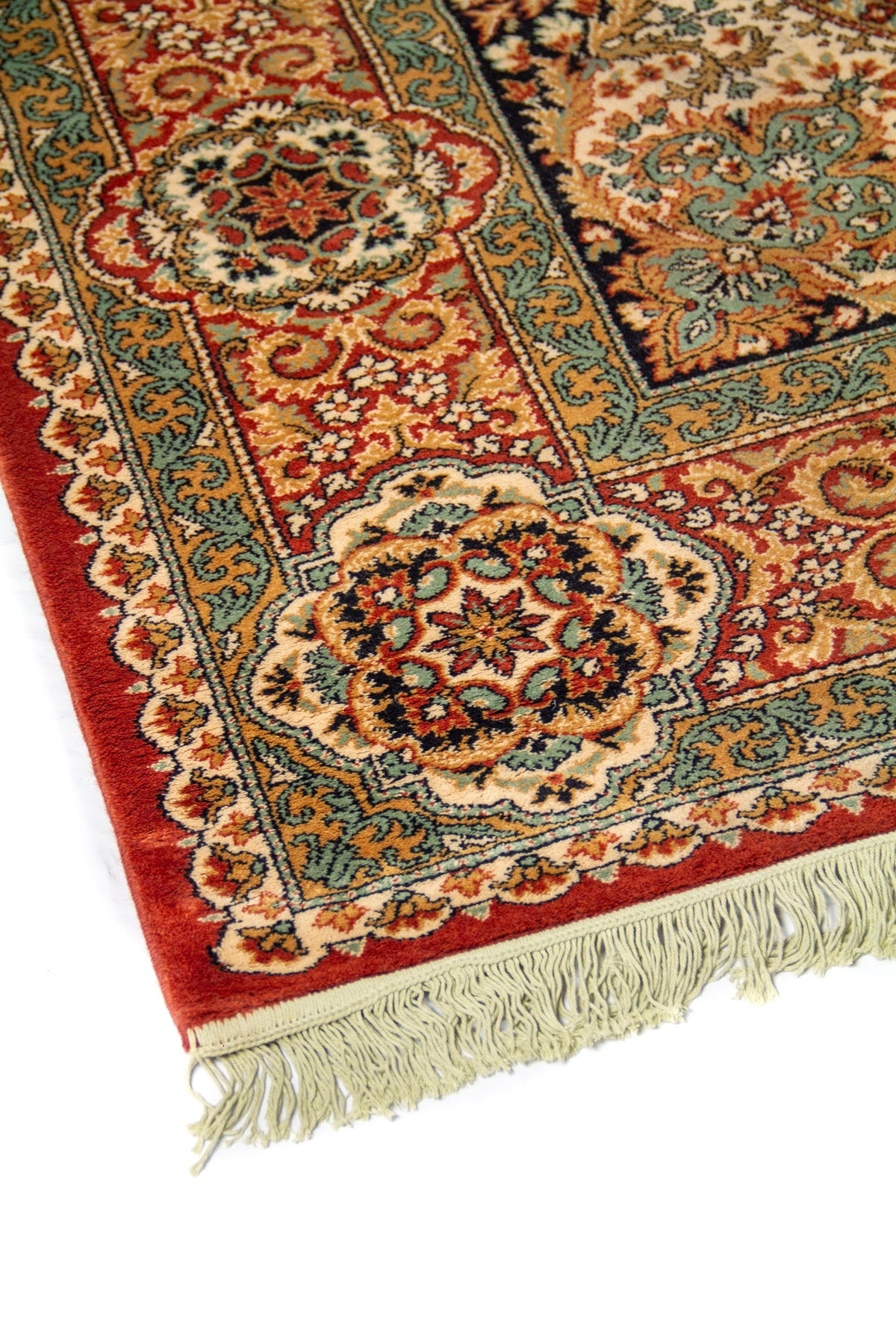Acercamiento del borde de alfombra clásica con motivos florales simétricos, líneas ornamentales y combinación de rojo, beige, celeste y azul oscuro.