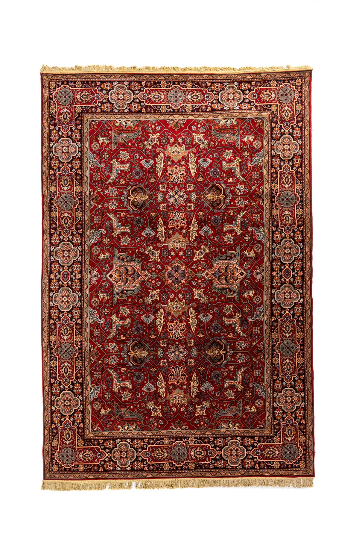 Alfombra clásica oriental en tonos rojo, azul oscuro, beige y anaranjado oscuro con diseño geométrico floral simétrico, amplia guarda ornamental y flecos en los extremos.