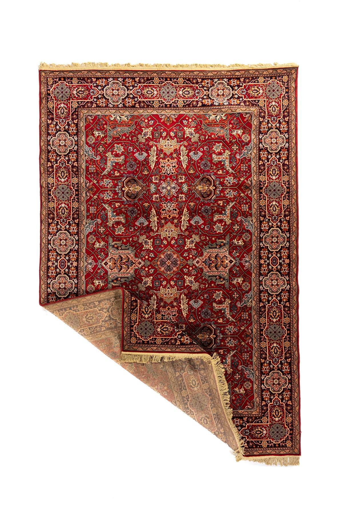 Alfombra oriental roja con una esquina doblada que muestra el reverso, la estructura del tejido, la guarda decorativa y los flecos beige.
