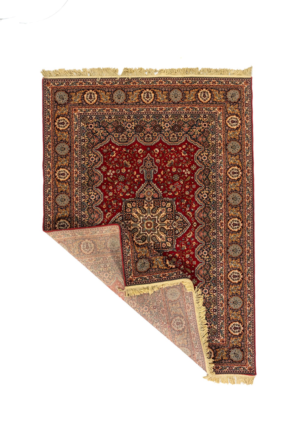 Alfombra oriental rectangular con una esquina doblada que muestra el reverso, los flecos y la estructura del tejido