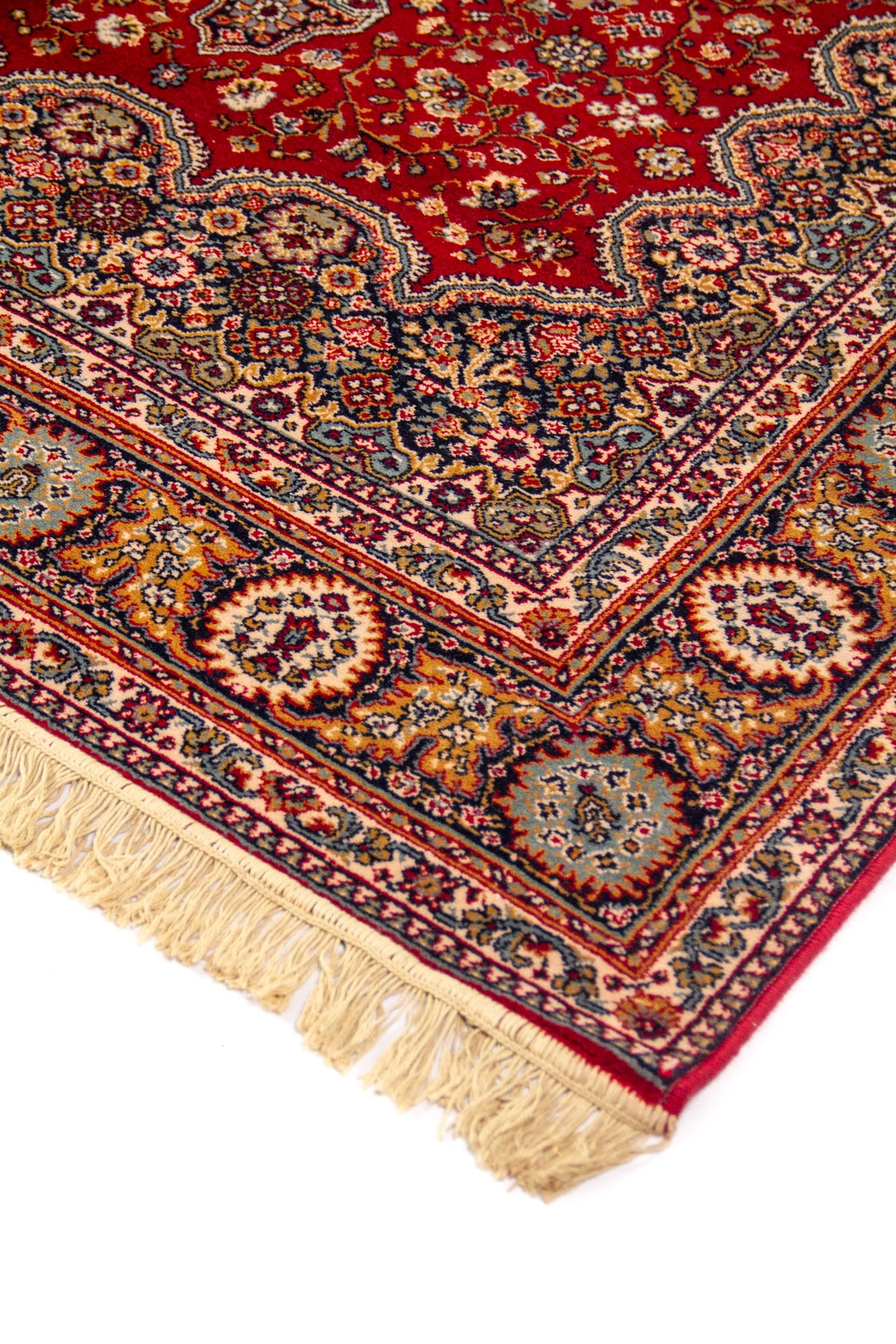 Detalle de esquina de alfombra roja con borde decorativo en tonos beige, azul y dorado, y flecos claros