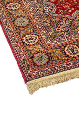 Primer plano del borde de alfombra clásica con motivos florales ornamentales y flecos en uno de los extremos