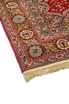 Primer plano del borde de alfombra clásica con motivos florales ornamentales y flecos en uno de los extremos