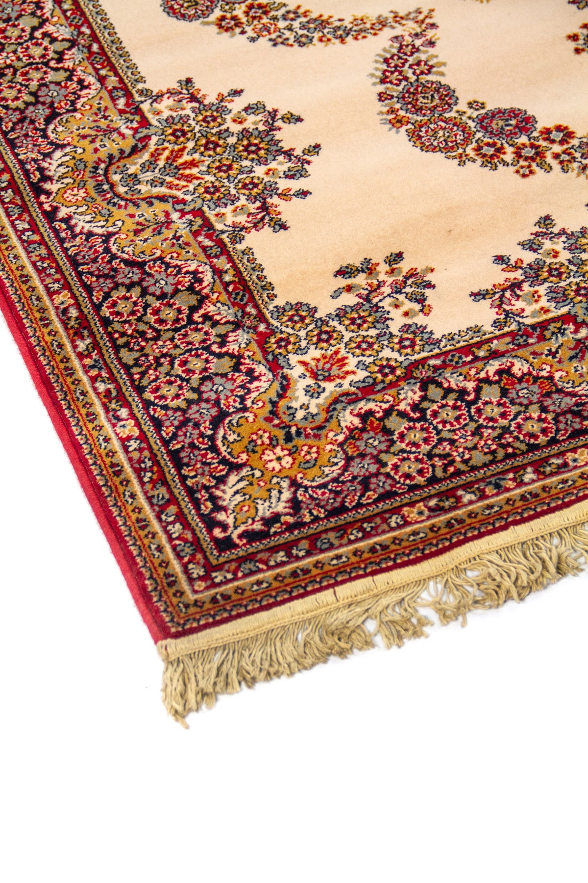 Primer plano del borde de alfombra oriental con fondo beige, motivos florales curvos y terminación con flecos