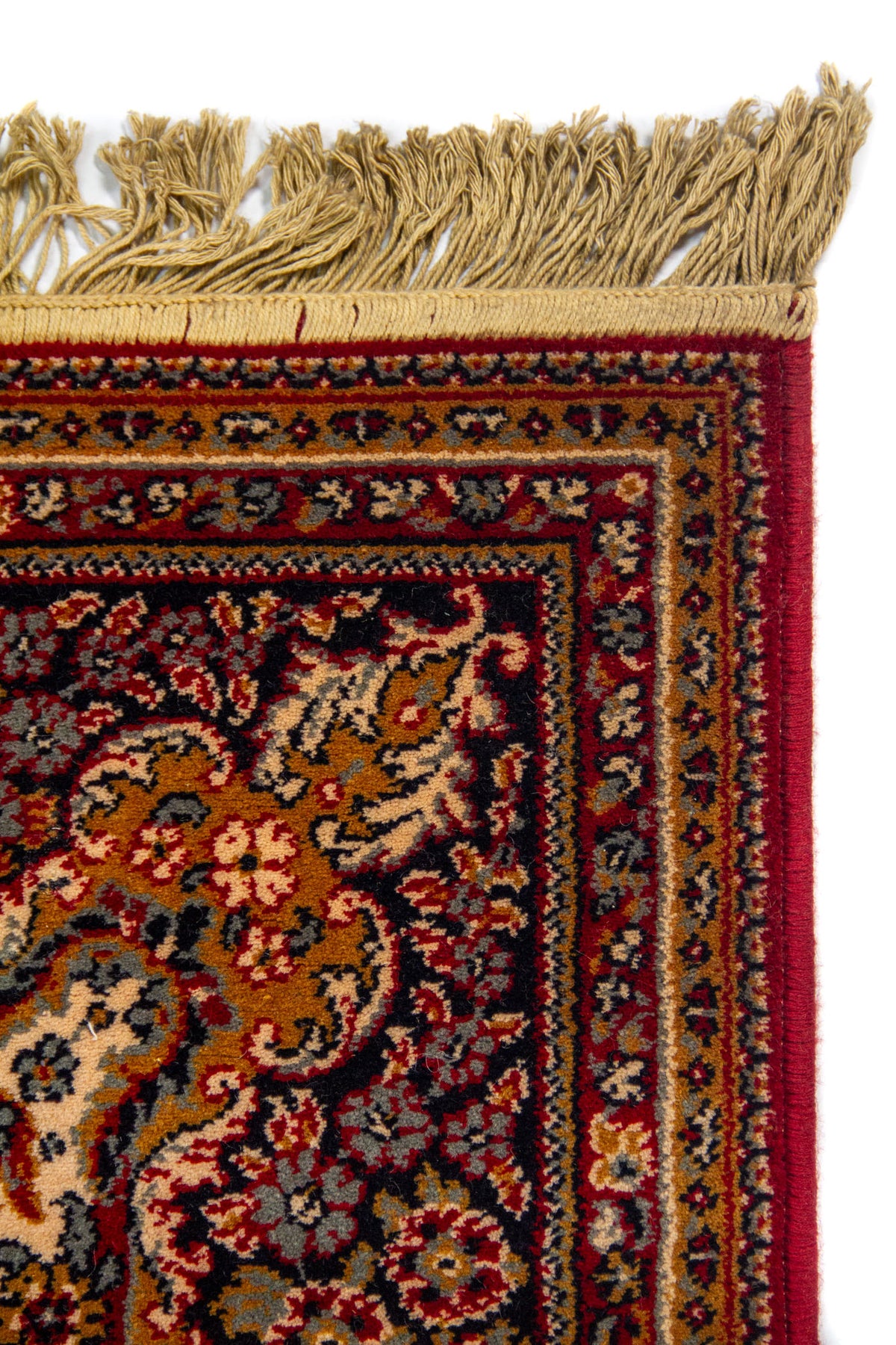Detalle de esquina superior de alfombra clásica con flecos beige y guarda decorativa en tonos rojo, azul oscuro y dorado