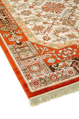 Primer plano de alfombra oriental con fondo blanco suave, patrón geométrico central y guarda ornamental en rojo, verde y negro