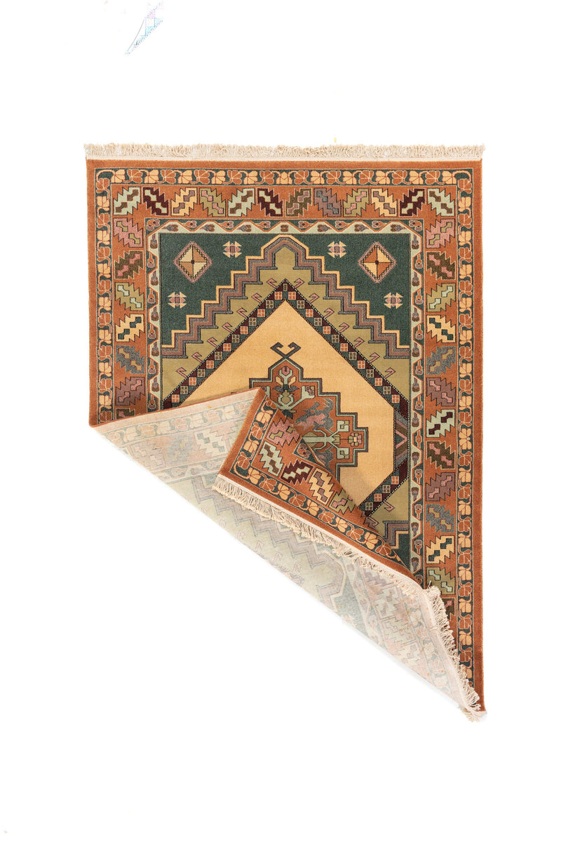 Alfombra clásica rectangular con una esquina doblada que muestra el reverso del tejido, los flecos y el detalle del diseño geométrico
