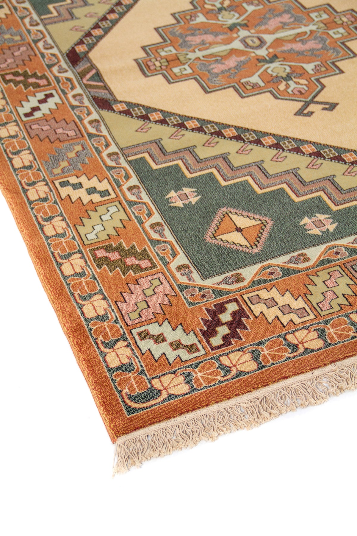 Primer plano de alfombra oriental con diseño geométrico central en tonos beige, verde oscuro, anaranjado oscuro y rosa suave