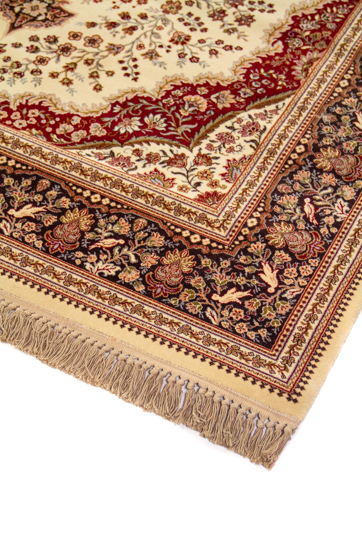 Detalle de esquina de alfombra oriental con flecos beige, guarda floral azul oscuro y patrones delicados en tonos blanco suave y rojo oscuro.