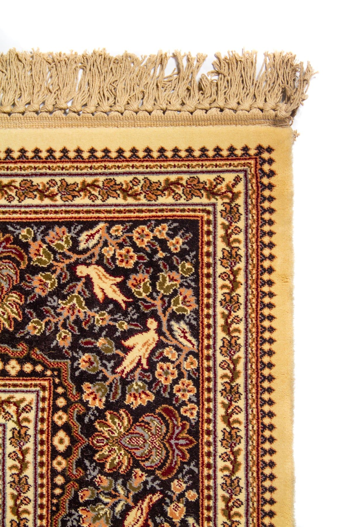 Detalle superior de alfombra oriental en color blanco suave con flecos beige y guarda ornamental de inspiración tradicional.