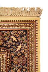 Detalle superior de alfombra oriental en color blanco suave con flecos beige y guarda ornamental de inspiración tradicional.