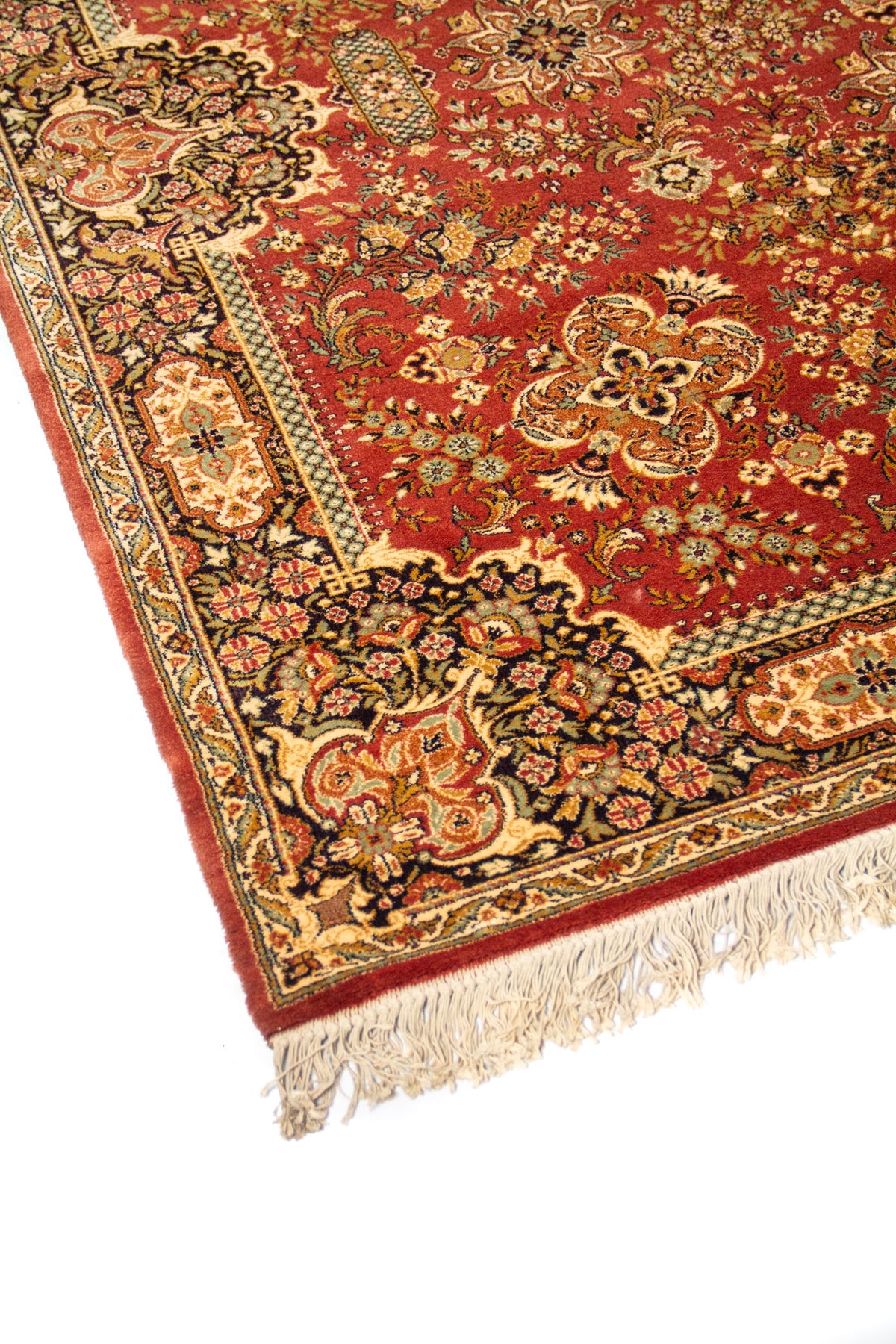 Acercamiento lateral de alfombra oriental con fondo anaranjado oscuro, diseño floral detallado y guarda decorativa en tonos beige, azul oscuro y verde.