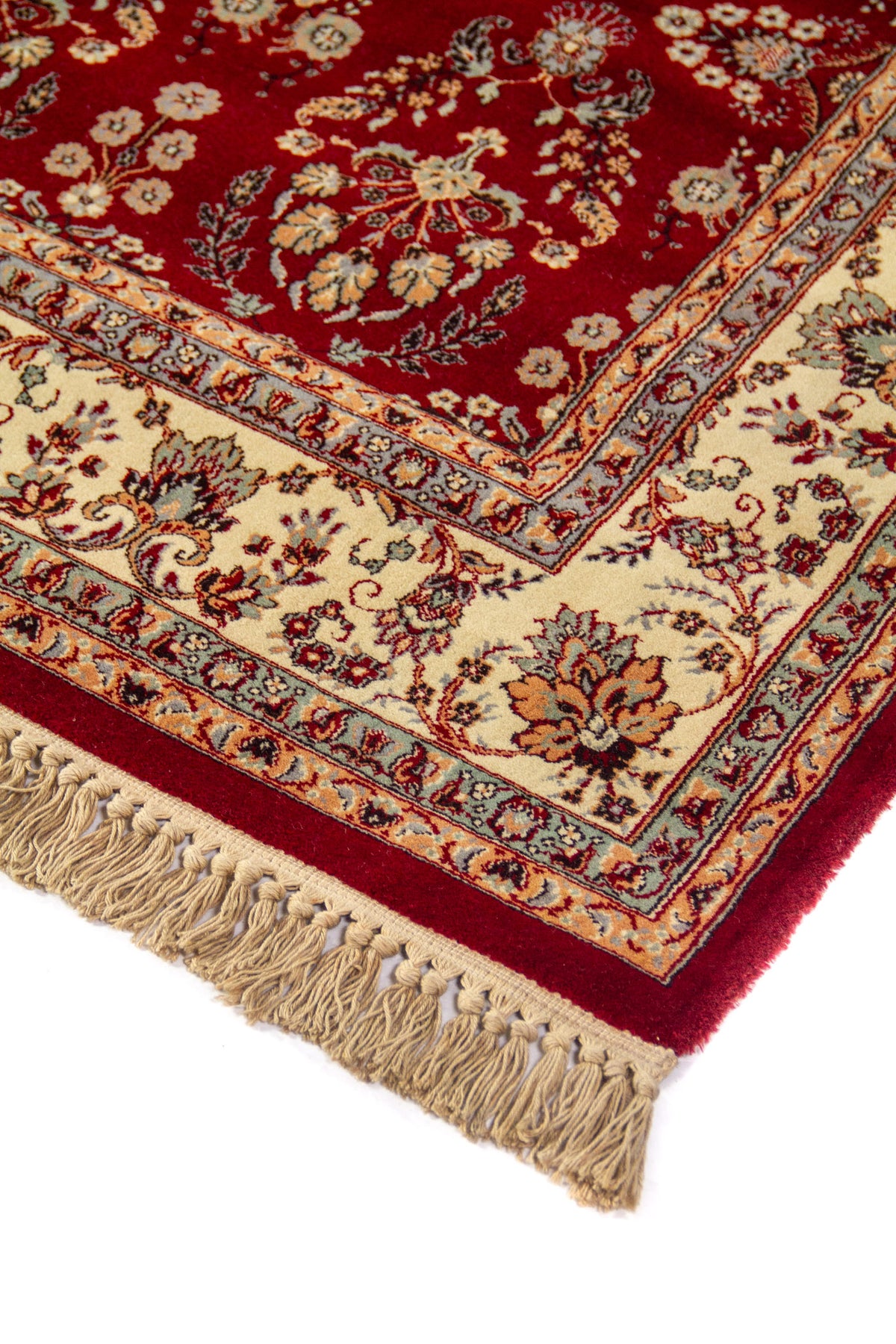 Primer plano del borde de una alfombra clásica roja con diseño floral, marco beige decorativo y acabado con flecos anudados
