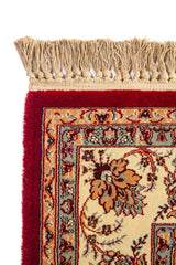 Detalle de esquina superior de alfombra roja con flecos beige, borde floral ornamentado y combinación de tonos blanco suave, azul suave y dorado.