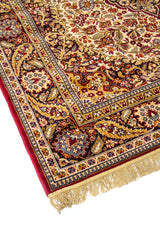Primer plano de alfombra clásica con motivos florales ornamentales, medallón central y guarda decorativa en tonos rojo oscuro, azul y beige