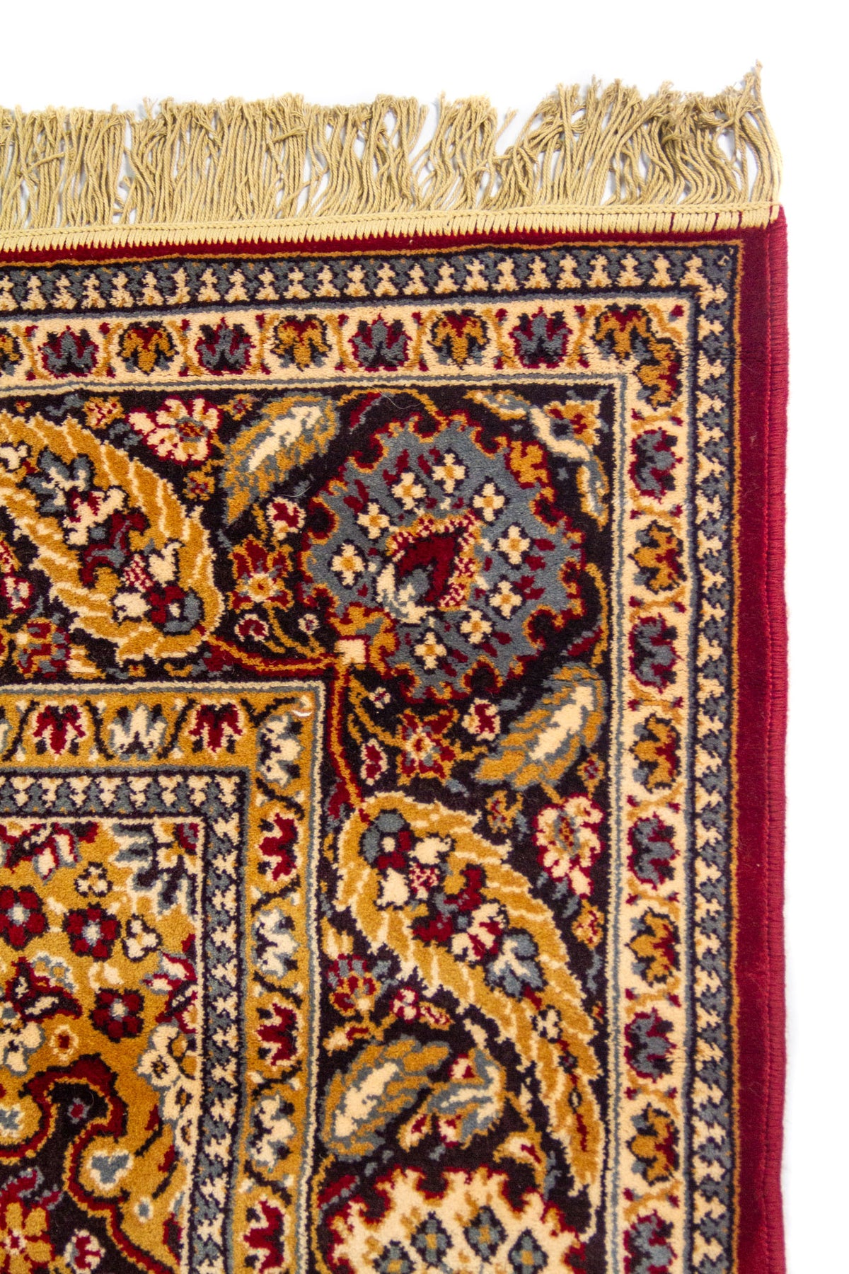 Detalle lateral de alfombra oriental con flecos beige y borde floral tradicional en tonos azul oscuro, dorado y rojo oscuro