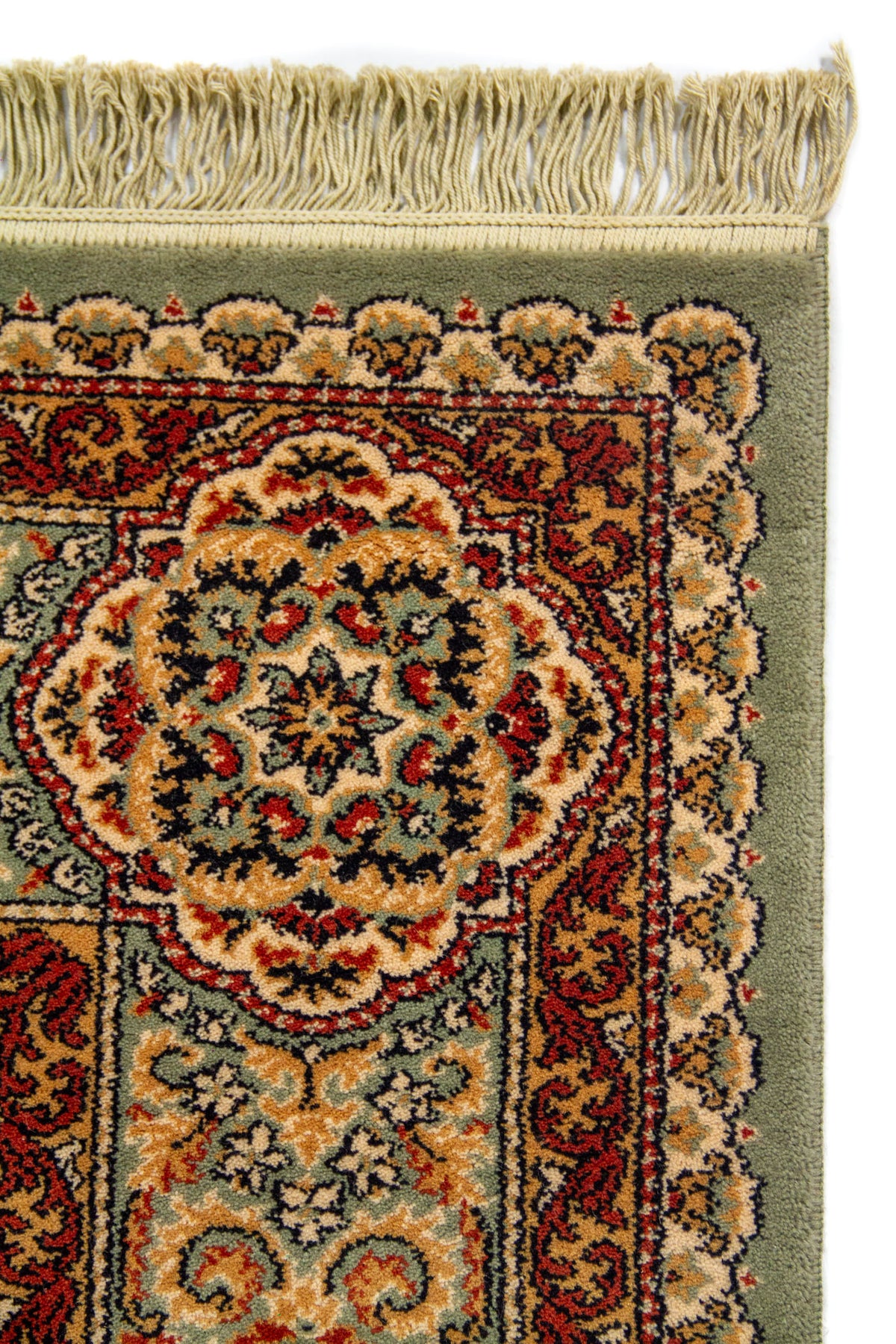 Detalle de esquina superior de alfombra clásica con flecos beige y borde decorativo en tonos verde, rojo, beige y azul oscuro