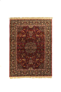 Alfombra clásica de estilo oriental en color rojo con medallón central, guarda azul marino y flecos beige.