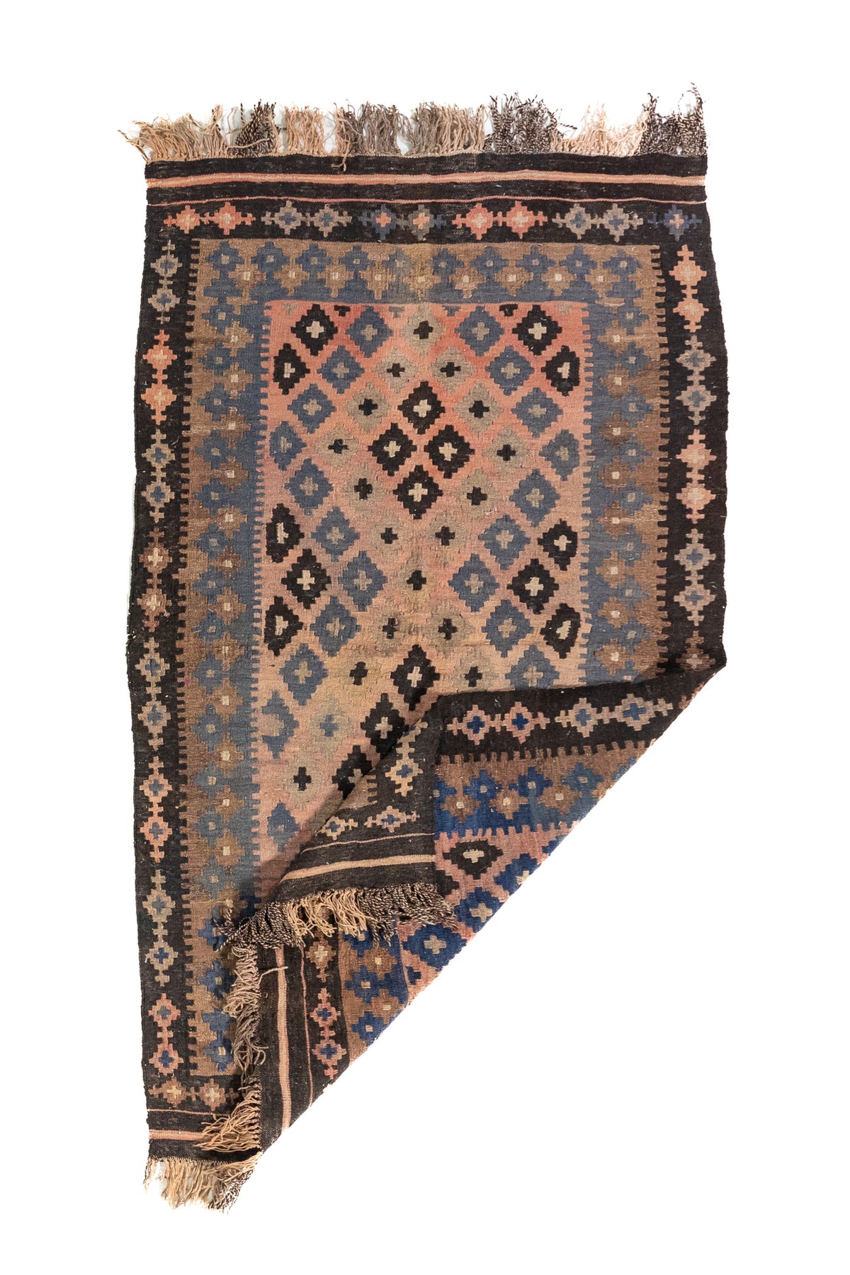 Alfombra geométrica de estilo tribal con una esquina doblada, en colores rosa, azul, marrón y negro, que muestra su textura y flexibilidad.