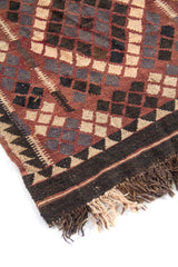 Acercamiento al diseño central de alfombra con rombos entrecruzados y pequeños patrones geométricos en marrón, negro, beige y gris