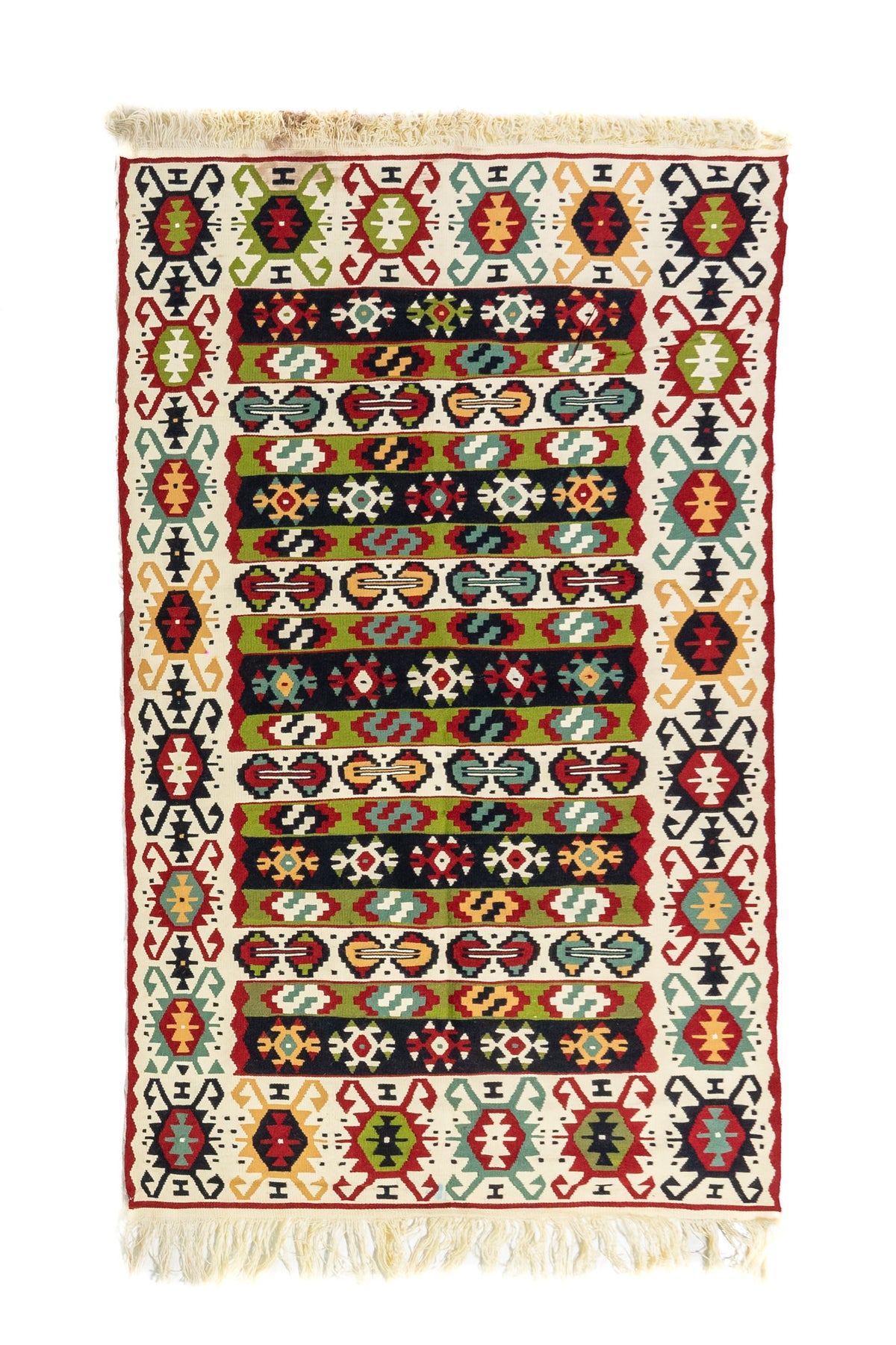Alfombra rectangular tipo kilim en tonos blanco suave, rojo, verde, celeste y negro, con diseño geométrico multicolor y flecos en ambos extremos.
