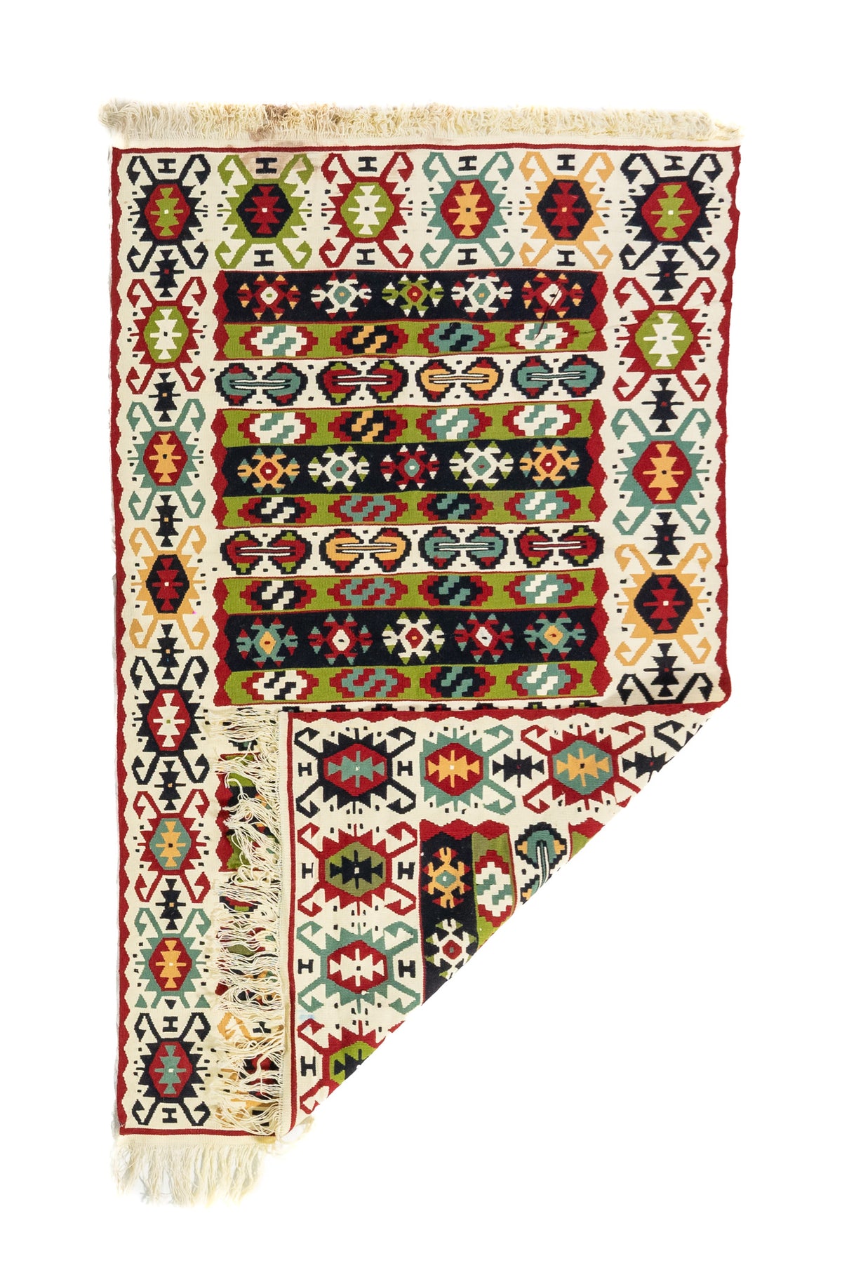 Alfombra geométrica artesanal con una esquina doblada, en colores, blanco, rojo, verde y negro, que muestra su textura y flexibilidad.