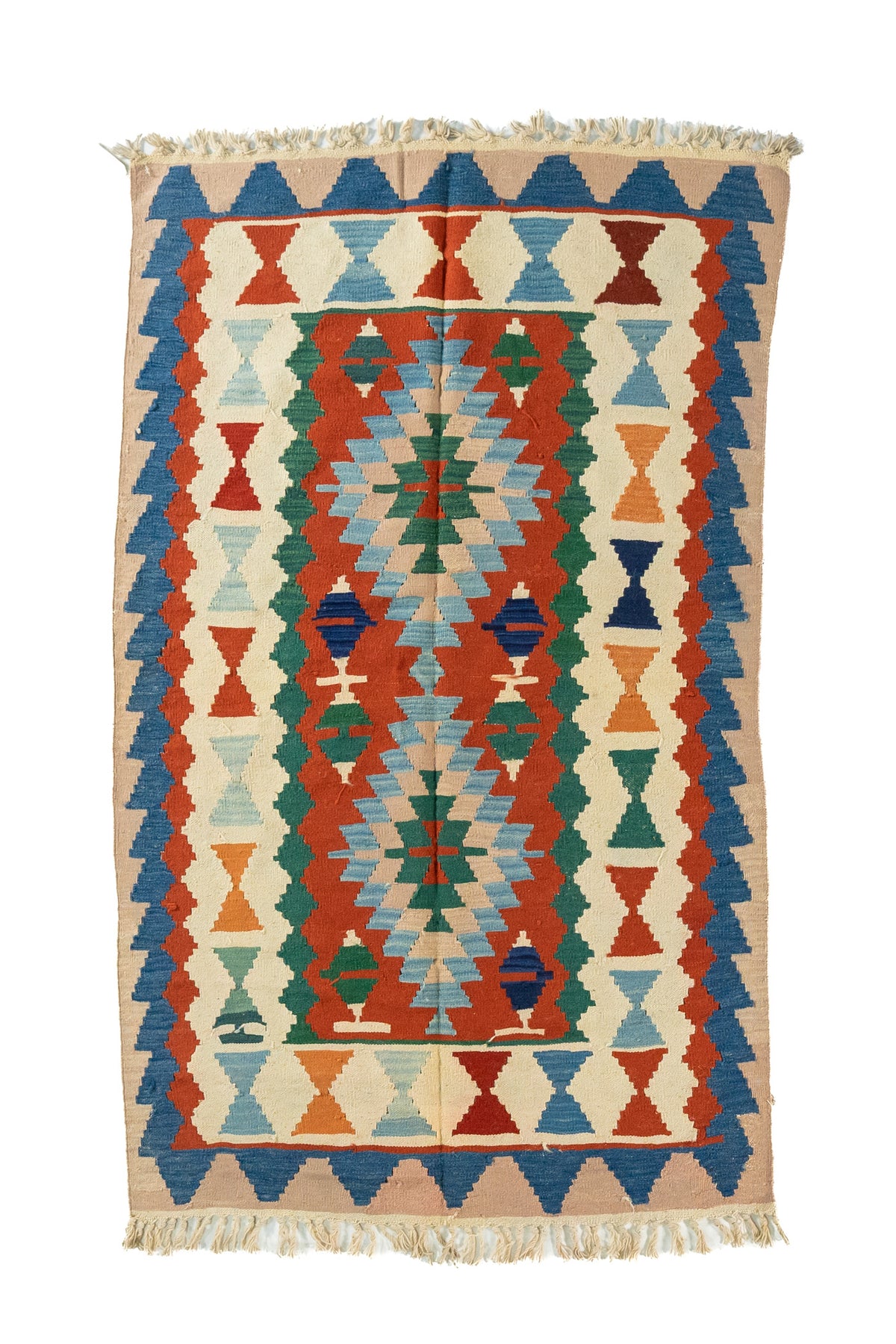 Alfombra rectangular artesanal en tonos beige, azul, rojo, verde, con diseño geométrico simétrico y flecos en ambos extremos.