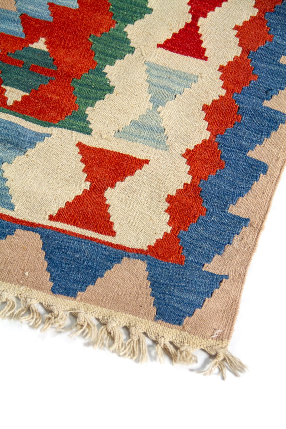 Acercamiento al diseño lateral de alfombra artesanal con motivos geométricos repetitivos en azul, rojo y beige, y textura de tejido visible.