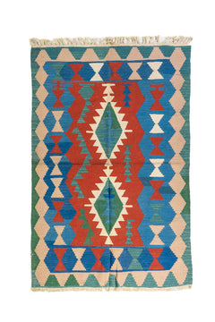 Alfombra estilo kilim con diseño geométrico en tonos rojo, azul, verde y beige.
