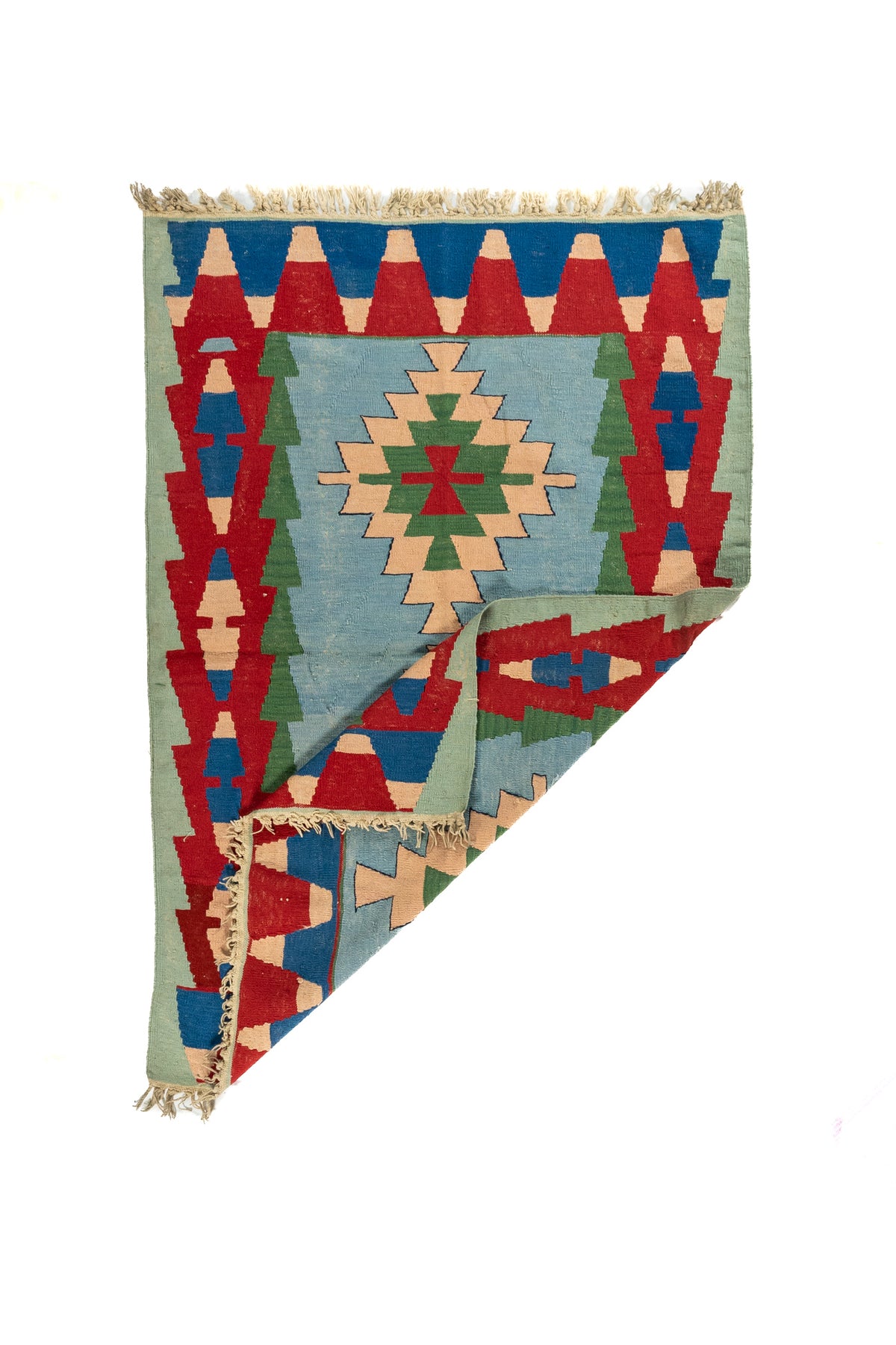 Alfombra geométrica tipo kilim con una esquina doblada que deja ver el reverso y su tejido artesanal.