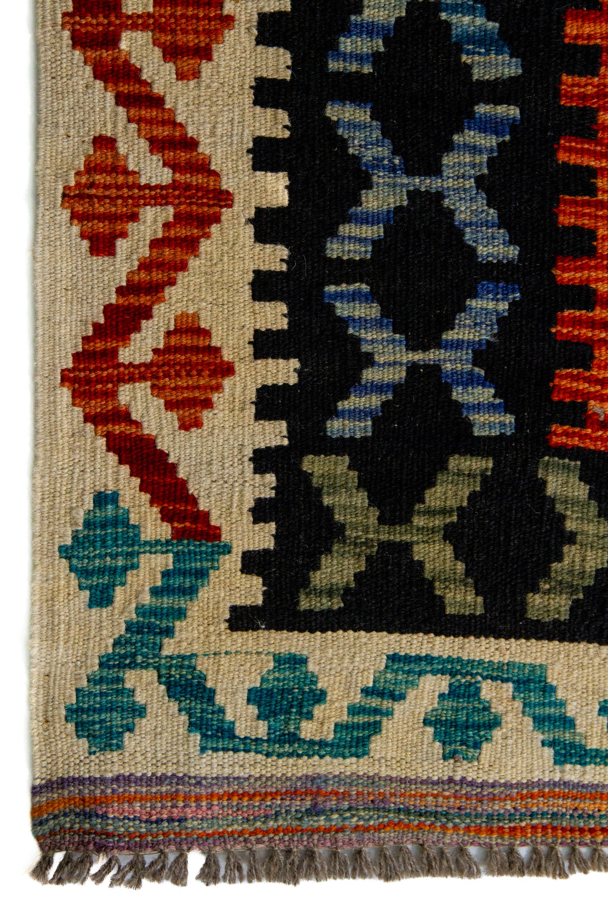 Detalle de guarda y flecos de alfombra Kilim multicolor con motivos geométricos