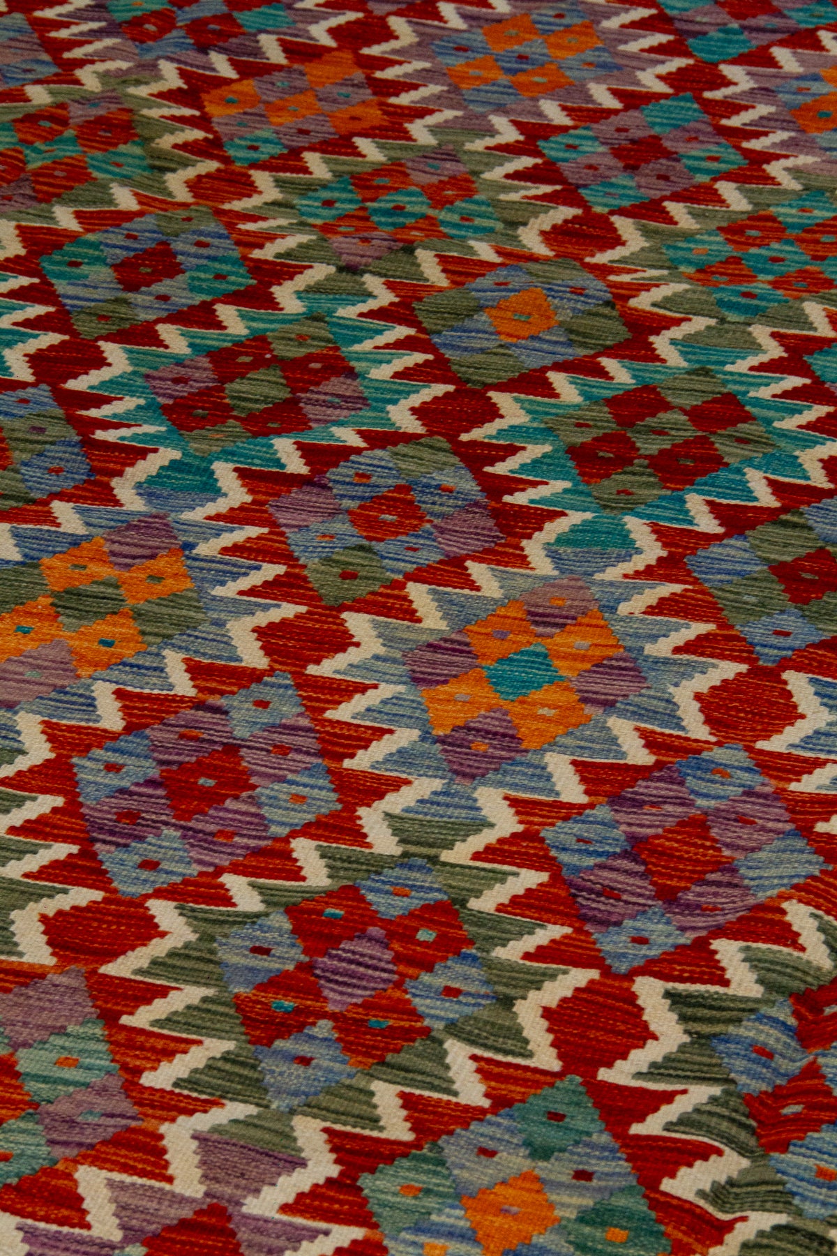 Detalle de textura de alfombra Kilim con rombos geométricos en violeta y naranja