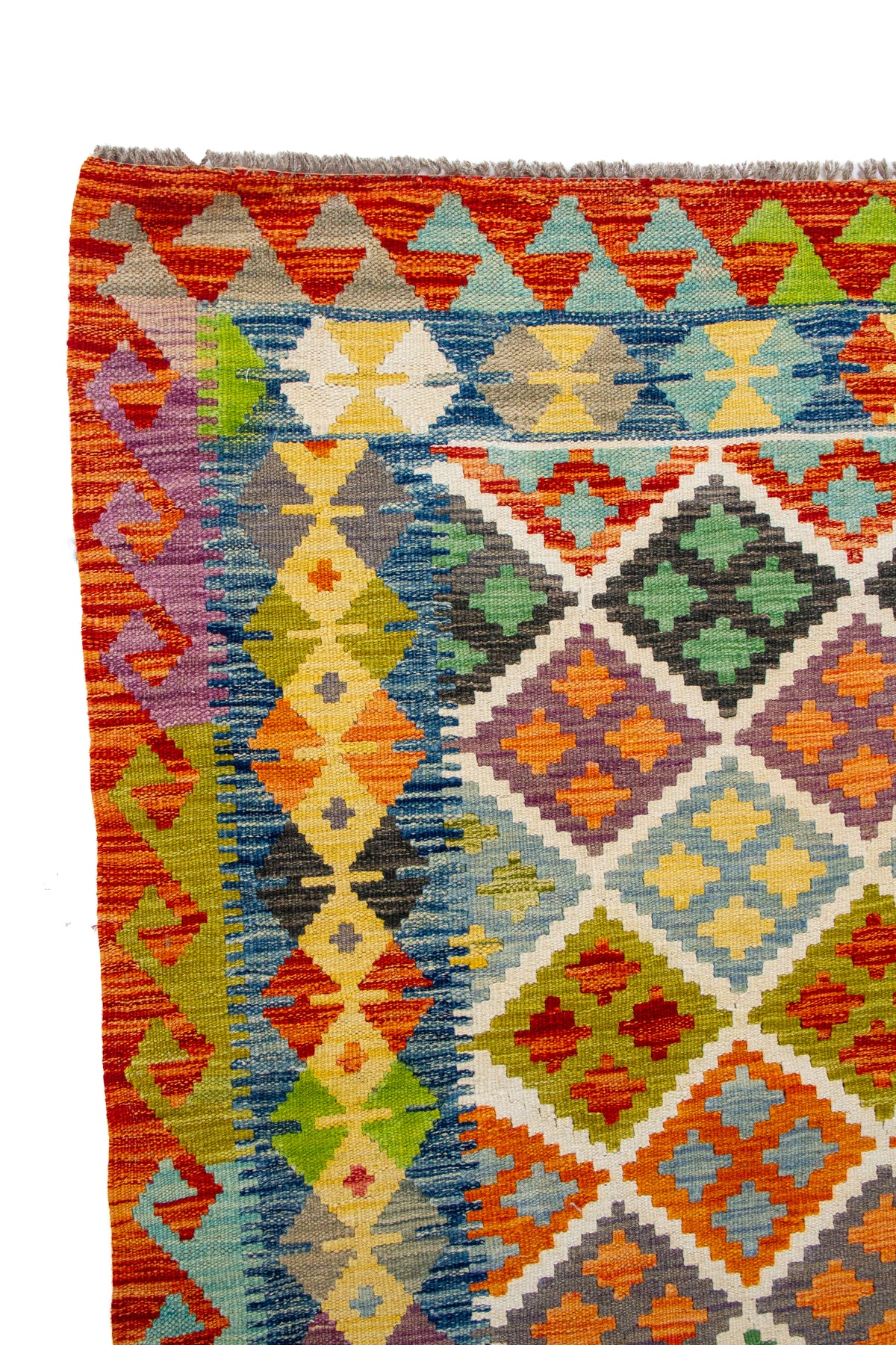 Detalle de guarda y flecos de alfombra Kilim con diseño geométrico en rojo, azul y verde