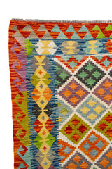Detalle de guarda y flecos de alfombra Kilim con diseño geométrico en rojo, azul y verde