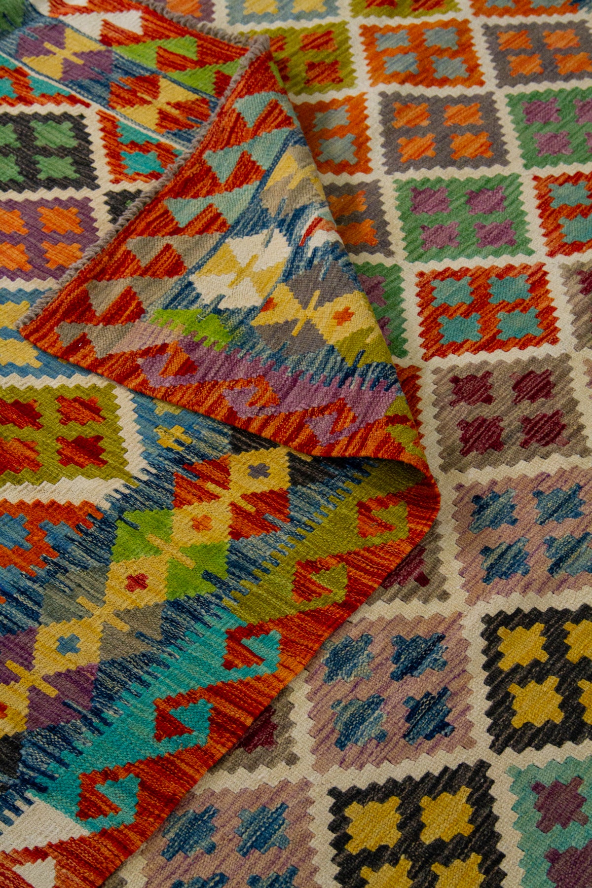 Detalle de textura y pliegue de alfombra Kilim con guardas tribales en tonos vivos