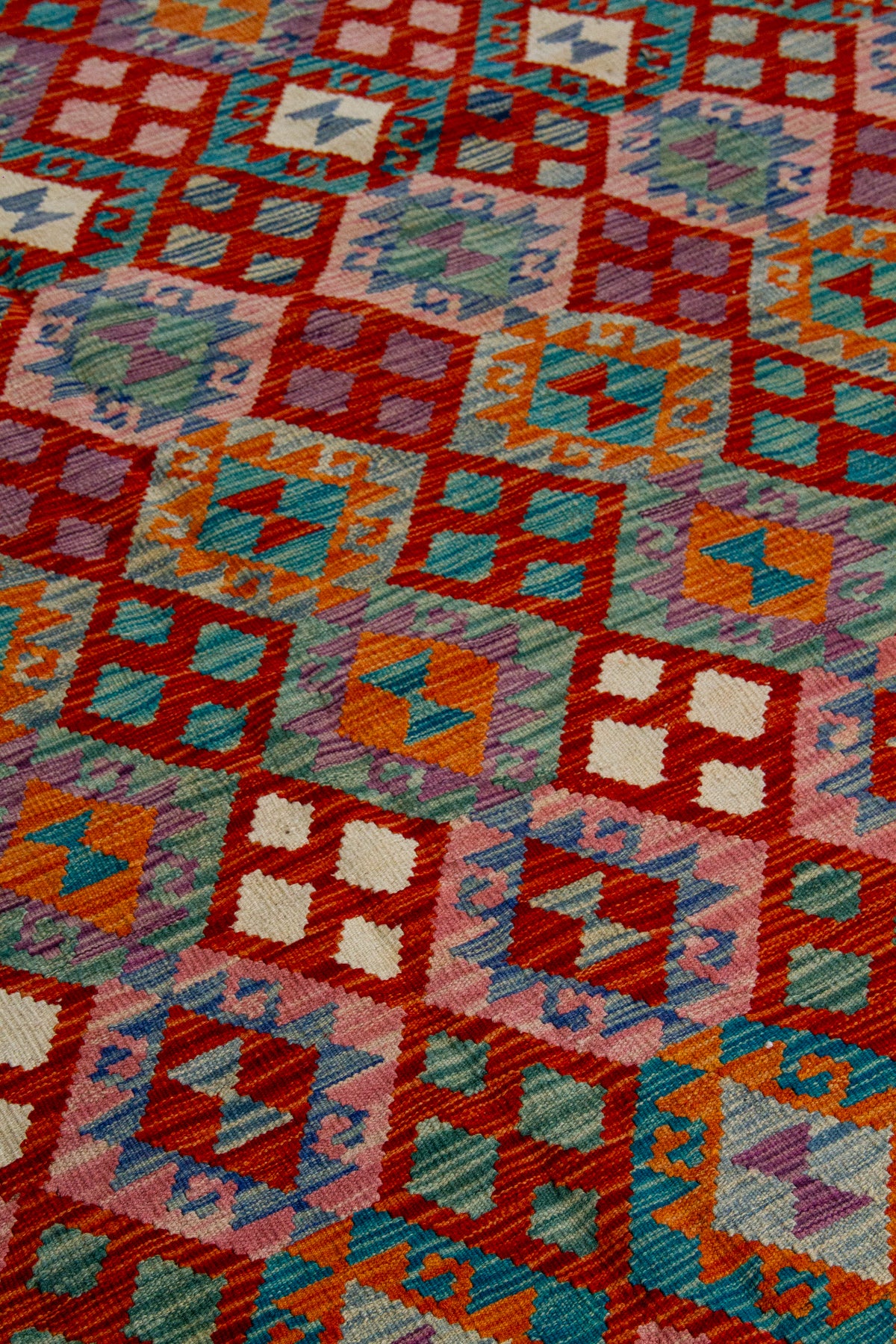 Detalle de textura de alfombra Kilim con diseño geométrico en rosa y naranja
