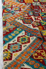 Detalle del borde doblado de alfombra Kilim multicolor con guardas geométricas y textura visible