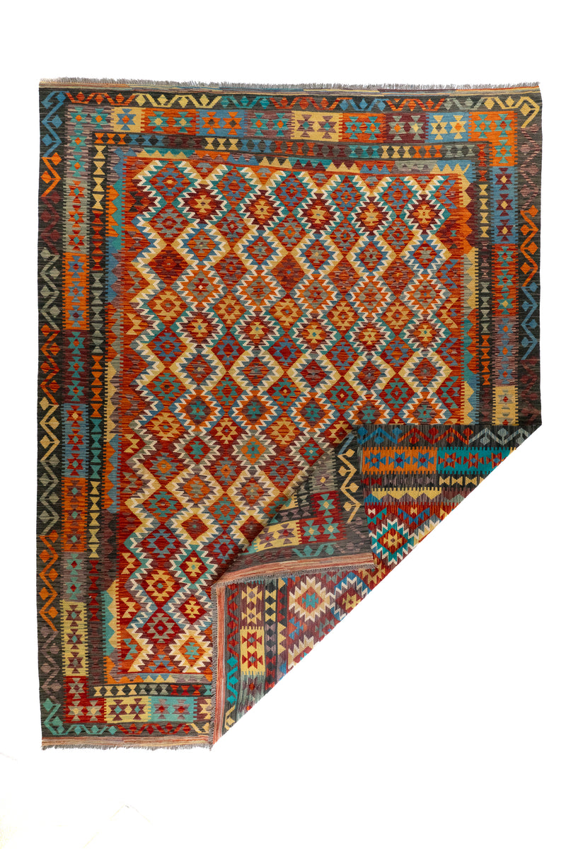 Alfombra Kilim multicolor con esquina doblada y diseño geométrico en tonos rojos y celeste