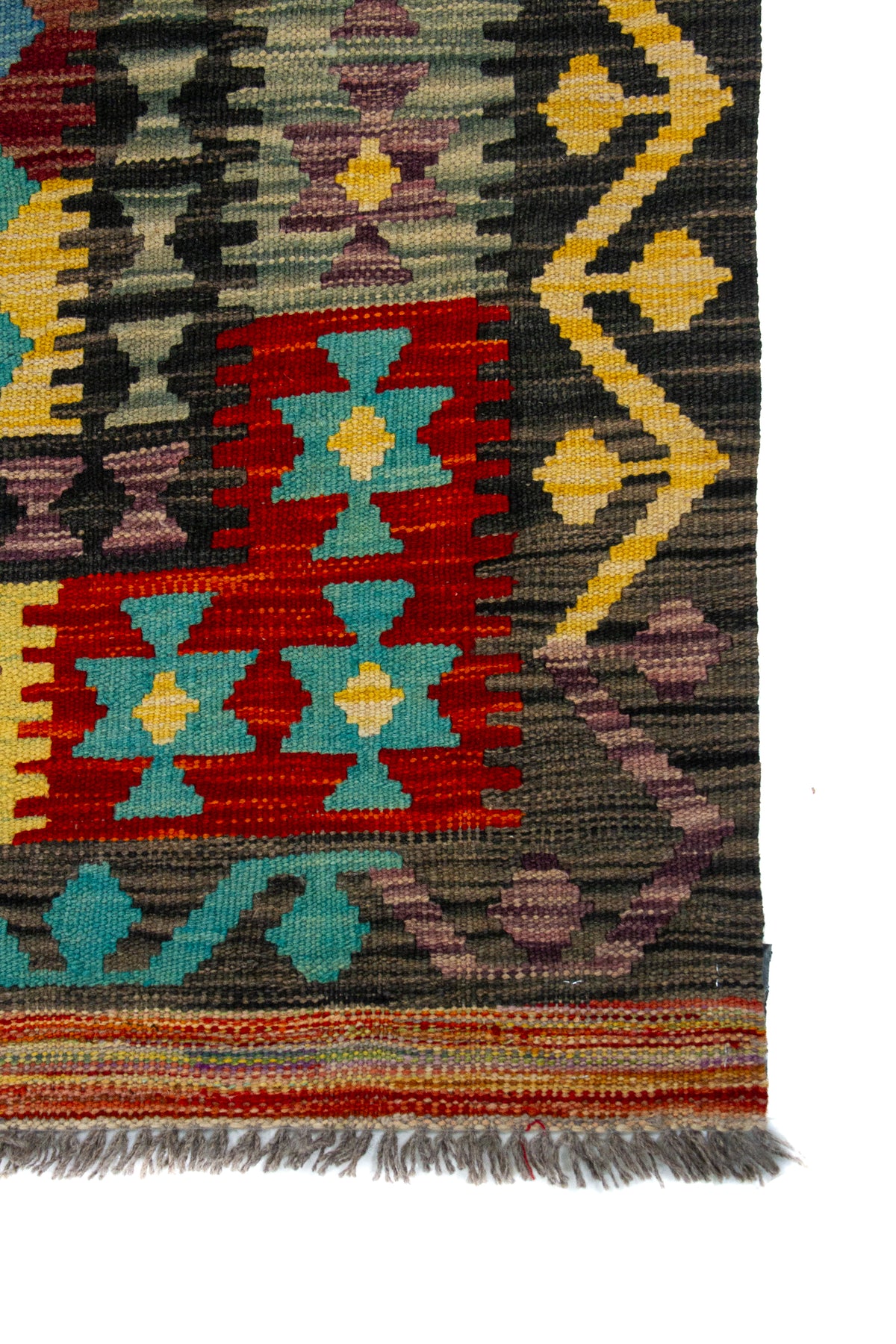 Detalle de guarda, textura y flecos de alfombra Kilim multicolor con diseño geométrico