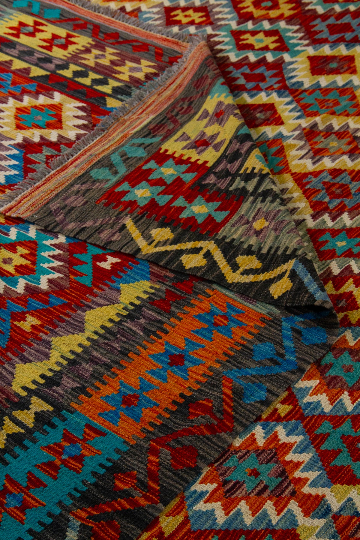 Detalle de textura y doblez de alfombra Kilim multicolor con motivos geométricos tradicionales
