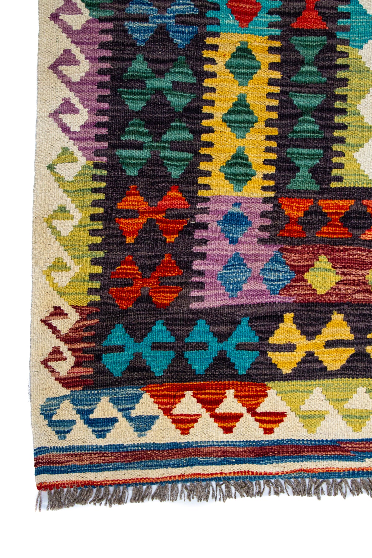 Detalle de guarda y flecos de alfombra Kilim multicolor con patrón geométrico