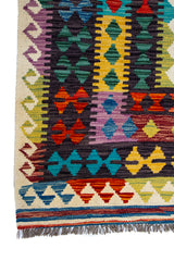 Detalle de guarda y flecos de alfombra Kilim multicolor con patrón geométrico