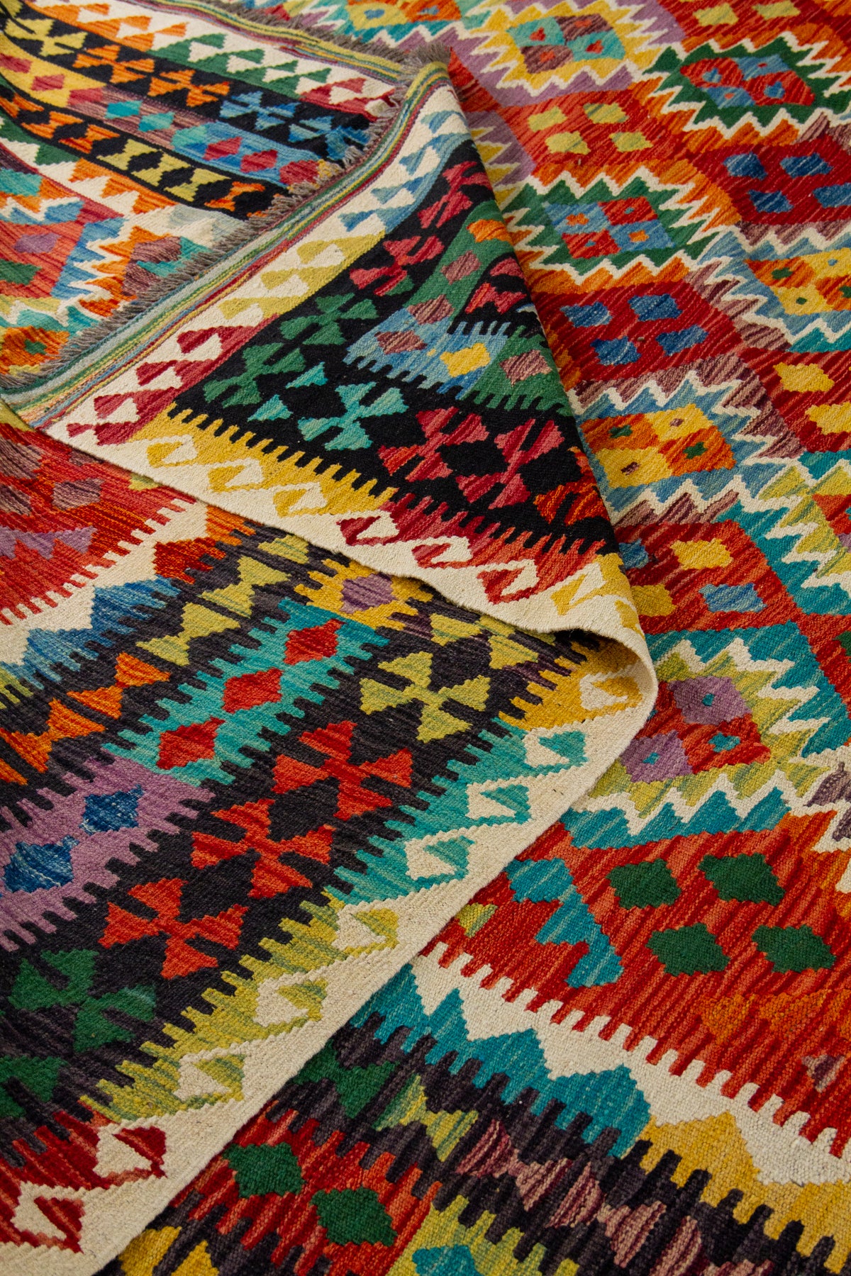 Detalle de textura y doblez de alfombra Kilim multicolor con guardas geométricas