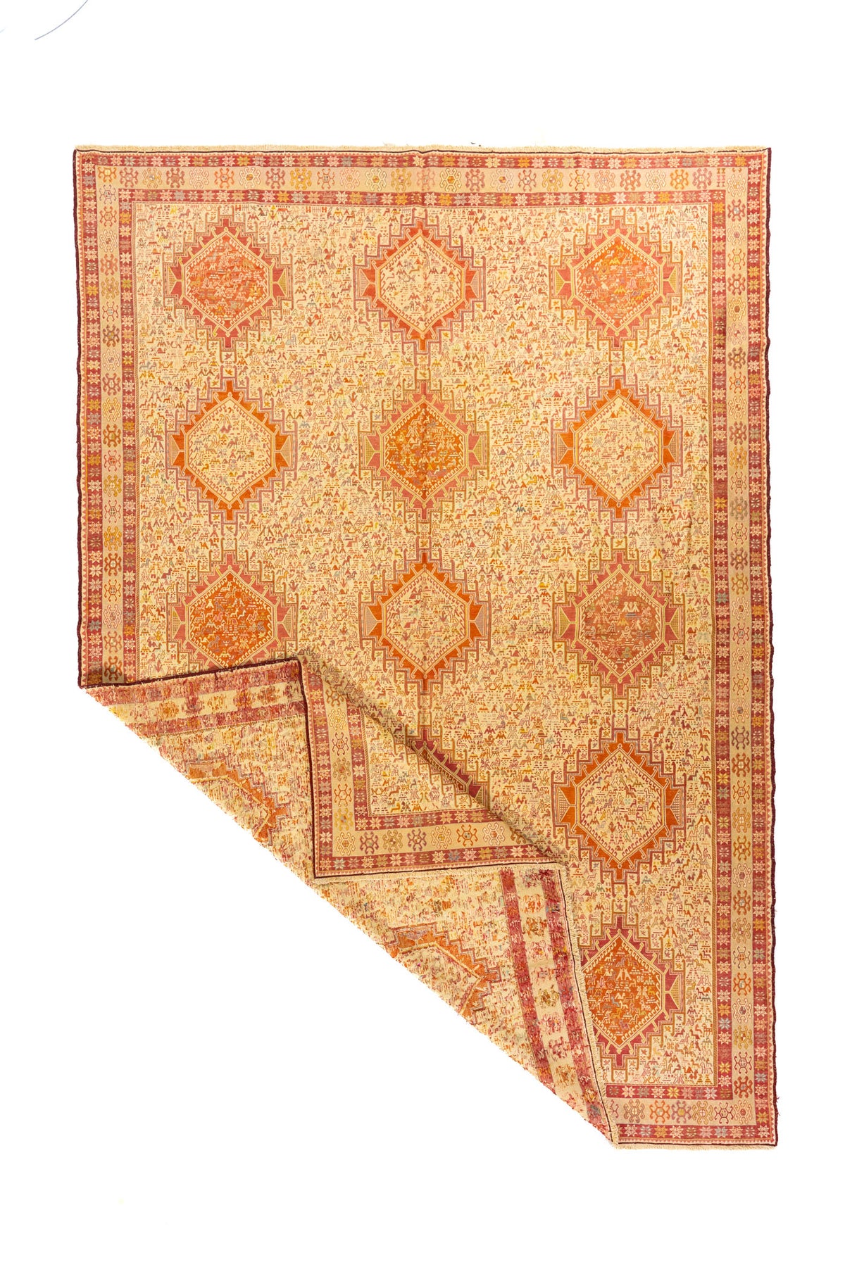 Alfombra geométrica en tonos cálidos con esquina doblada que muestra el reverso y el diseño completo