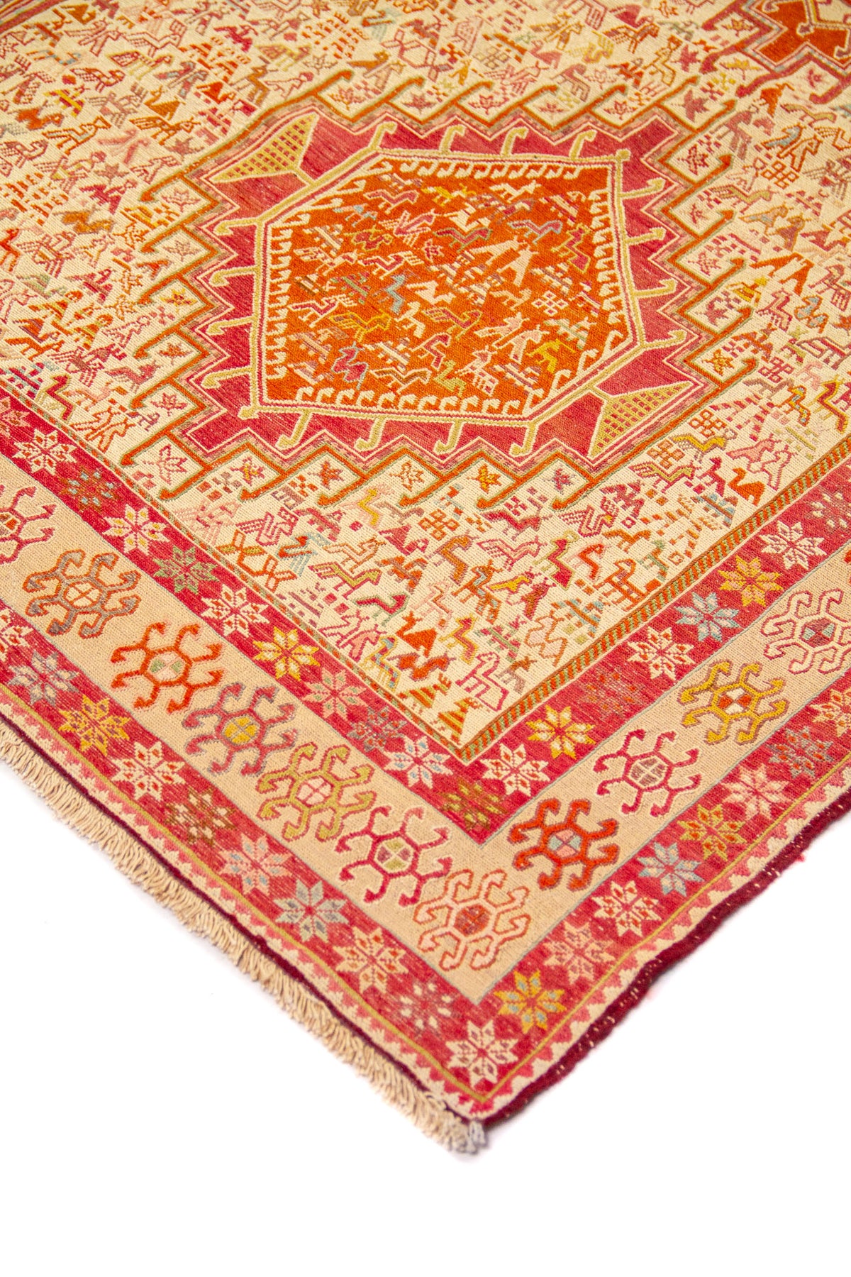 Detalle de esquina de alfombra con medallón geométrico rojo y guarda decorativa en rojo y beige