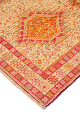 Detalle de esquina de alfombra con medallón geométrico rojo y guarda decorativa en rojo y beige