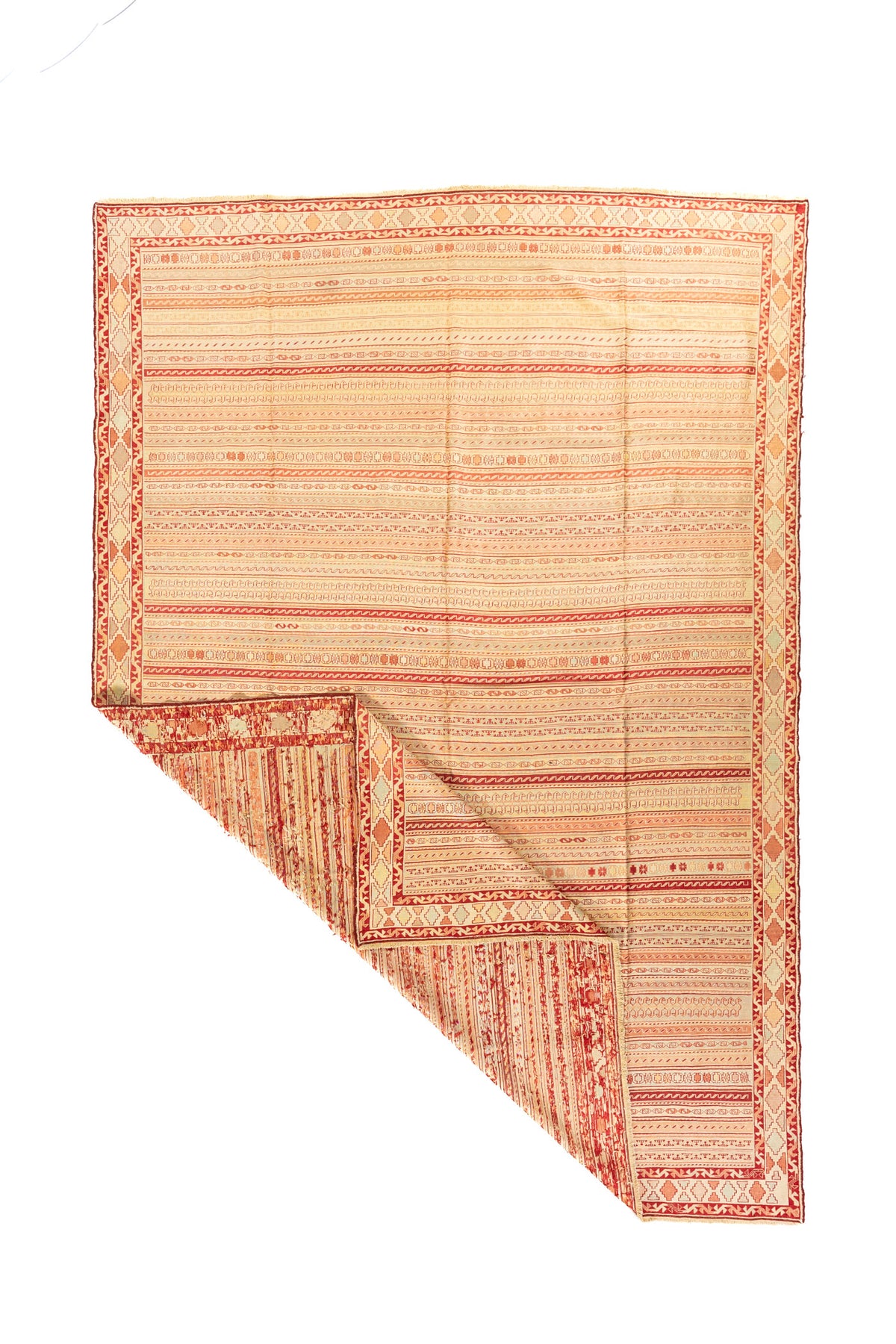 Alfombra tejida en tonos cálidos con una esquina doblada que muestra el reverso y su diseño lineal