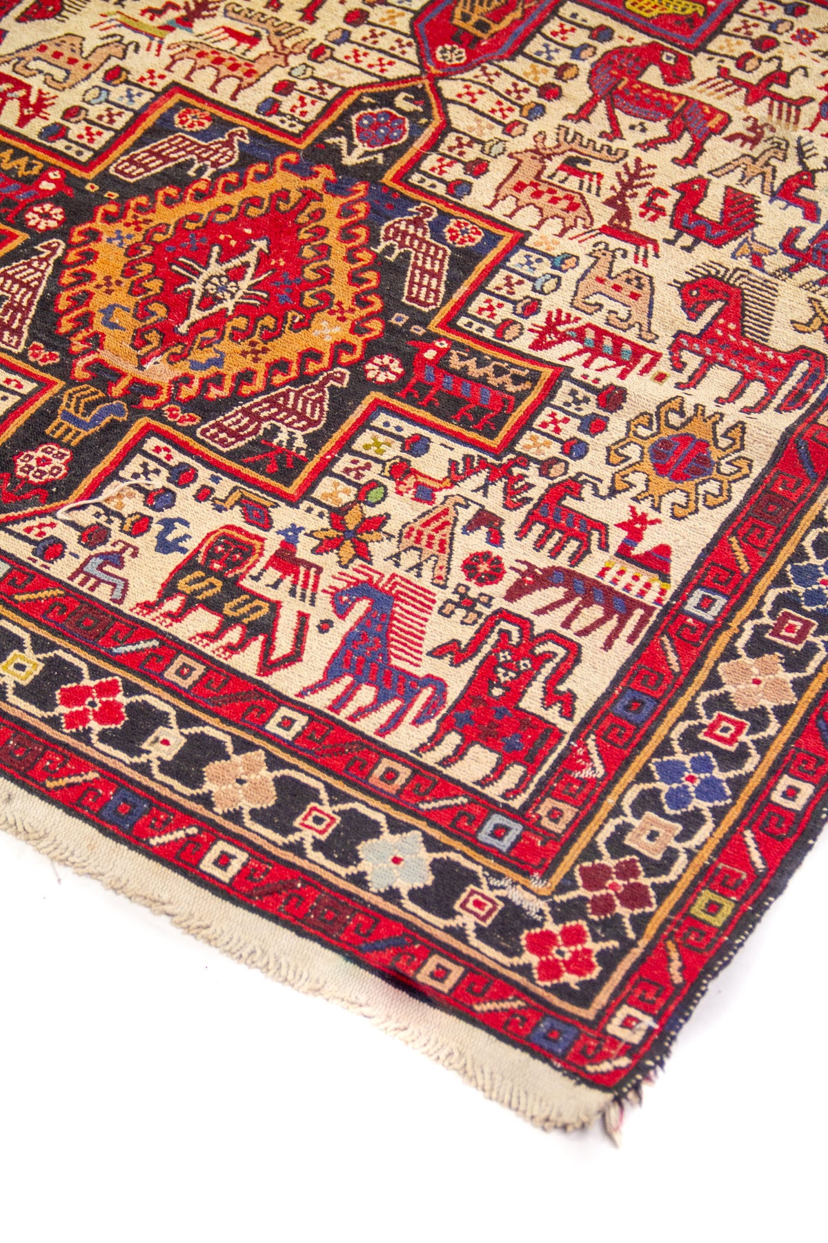 Detalle de alfombra oriental con medallón geométrico central y motivos de figura animal en tonos rojo, azul, beige y dorado.