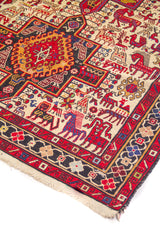 Detalle de alfombra oriental con medallón geométrico central y motivos de figura animal en tonos rojo, azul, beige y dorado.