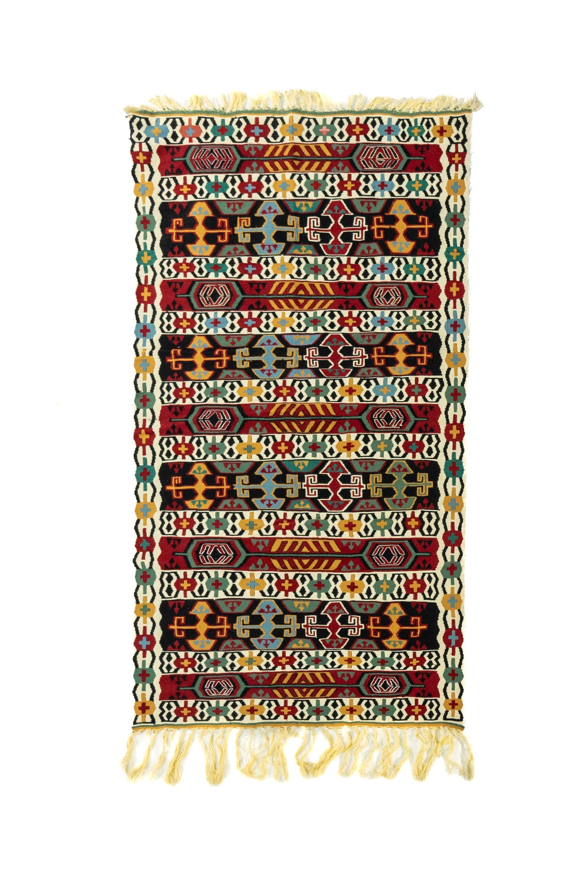 Alfombra artesanal rectangular con franjas geométricas en rojo, negro, blanco suave, verde, azul y dorado, con flecos en ambos extremos